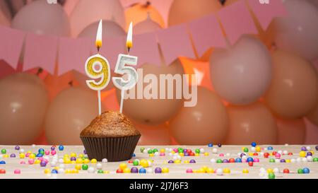 Ballons décorations et une bougie d'anniversaire heureuse avec un nombre dans un gâteau. Joyeux anniversaire voeux en couleurs roses pour une fille, espace copie. Muffin Banque D'Images