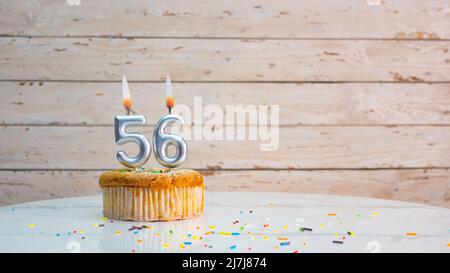 Joyeux anniversaire chiffres argentés sur les tableaux blancs arrière-plan de l'espace de copie. Belle carte d'anniversaire avec un cupcake et une bougie Banque D'Images