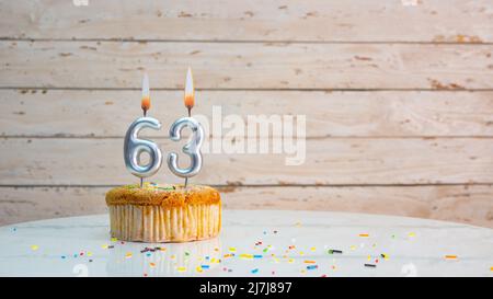 Joyeux anniversaire chiffres argentés sur les tableaux blancs arrière-plan de l'espace de copie. Belle carte d'anniversaire avec un cupcake et une bougie Banque D'Images