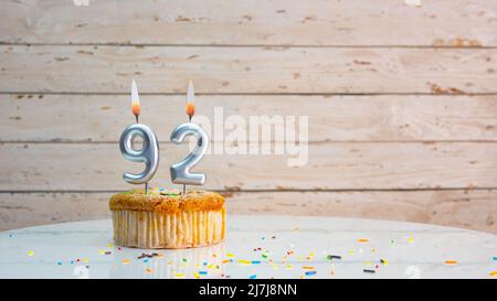 Joyeux anniversaire chiffres argentés sur les tableaux blancs arrière-plan de l'espace de copie. Belle carte d'anniversaire avec un cupcake et une bougie Banque D'Images