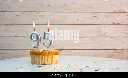 Joyeux anniversaire chiffres argentés sur les tableaux blancs arrière-plan de l'espace de copie. Belle carte d'anniversaire avec un cupcake et une bougie Banque D'Images