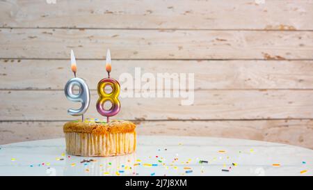 Joyeux anniversaire chiffres argentés sur les tableaux blancs arrière-plan de l'espace de copie. Belle carte d'anniversaire avec un cupcake et une bougie Banque D'Images