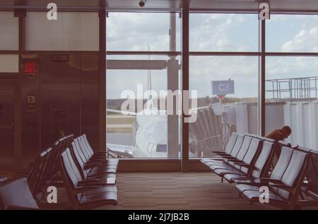 Vider les sièges de l'aéroport dans le terminal d'attente avec un avion stationné à l'extérieur. Banque D'Images