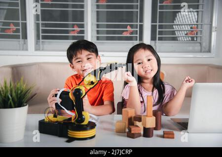 Deux enfants programmant et testant robot ARM leur science, Kid petite fille programme code au robot avec ordinateur portable et le garçon test avec la télécommande Banque D'Images