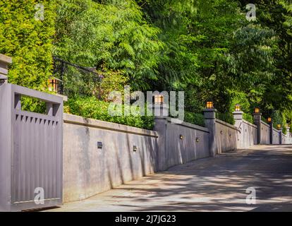 Mur extérieur de clôture en béton avec appliques murales. Clôture moderne en béton avec lampes de nuit sur les piliers. Photo de rue, personne, mise au point sélective Banque D'Images