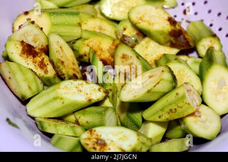 Des courgettes fraîches coupées dans un bol en plastique avec des épices, des poivrons rouges, du sel et du cumin prêts à être grillés avec de l'ail et de l'huile, des aliments sains, des légumes et nous Banque D'Images
