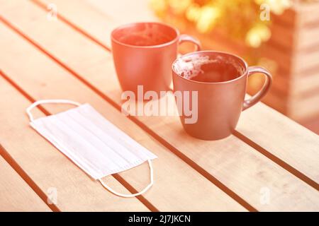 Deux boissons de café dans un café extérieur après avoir bu. Tasse désordonnée après le petit déjeuner. Masque de protection. latte dans une tasse. Déjeuner ambiance décontractée. Style de vie matin confortable. Personne Banque D'Images