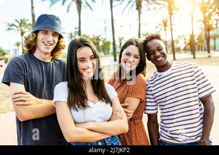 Groupe d'amis multiraciaux heureux posant à l'extérieur Banque D'Images