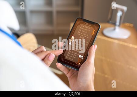 Jeune femme lisant le menu sur l'écran du téléphone mobile, gros plan Banque D'Images