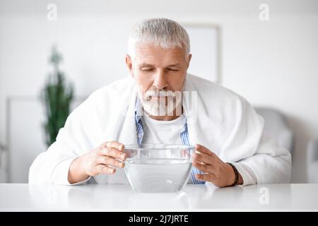 Homme mature qui fait inhalation de vapeur à la maison Banque D'Images