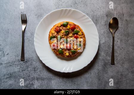 Pizza italienne très prisée dans une assiette blanche sur fond. Gros plan, mise au point sélective. Banque D'Images