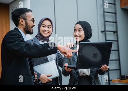 des hommes d'affaires musulmans discutent de l'utilisation d'un ordinateur portable à l'avant du bureau Banque D'Images