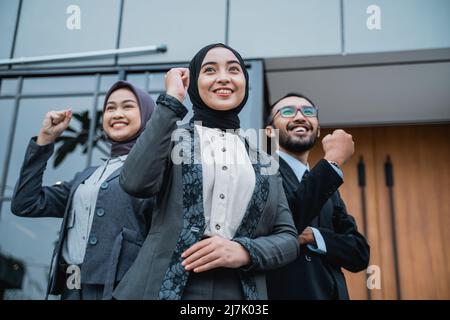 une femme d'affaires portant le hijab lève le bras pour montrer son succès Banque D'Images