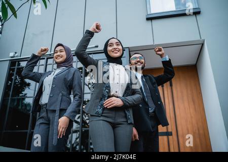 une femme d'affaires portant le hijab lève le bras pour montrer son succès Banque D'Images