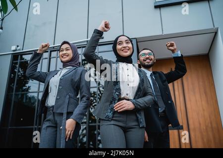 une femme d'affaires portant le hijab lève le bras pour montrer son succès Banque D'Images