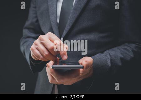 Un homme d'affaires élégant en costume gris foncé utilise un smartphone mobile, un gros plan de la saisie manuelle de messages texte, une mise au point sélective Banque D'Images