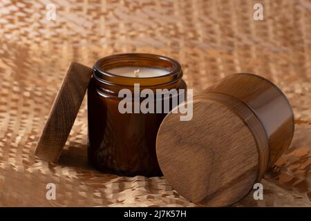 Bougies de soja dans un pot en verre brun avec un couvercle en bois. Aromathérapie. Bougie sur fond beige gros plan. Placer une étiquette. Cire et mèche. Décoration d'intérieur. Fait à la main. Désodorisant. Concept de bougie de soja Banque D'Images