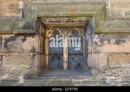 Cadre de fenêtre en pierre avec des formes de diamants en vitraux tenus en plomb dans une église médiévale Banque D'Images