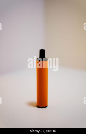 Cigarette électronique orange jetable sur fond blanc vif. Banque D'Images