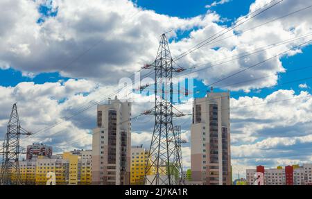 Lignes électriques dans la ville près de bâtiments résidentiels contre un ciel bleu. Concept d'électrification urbaine. Banque D'Images