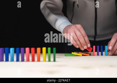 Photo conceptuelle des mains préparant une rangée de pierres domino. Effet Domino avec pierres colorées et espace de copie Banque D'Images
