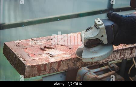 un homme meule une planche. Élimination de l'ancienne peinture des panneaux. Travail de menuiserie. Concentration sélective Banque D'Images