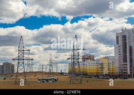 Lignes électriques dans la ville près de bâtiments résidentiels contre un ciel bleu. Concept d'électrification urbaine. Banque D'Images