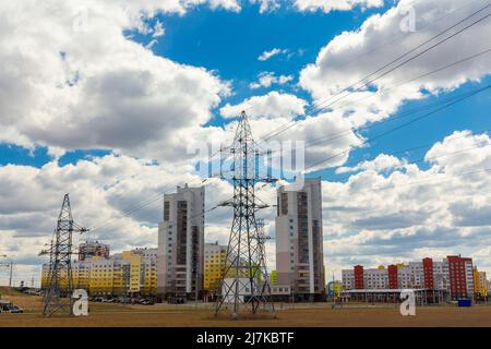 Lignes électriques dans la ville près de bâtiments résidentiels contre un ciel bleu. Concept d'électrification urbaine. Banque D'Images