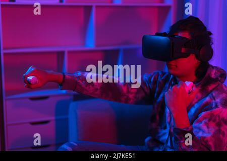 Concept de technologie métaverse, Homme porte des lunettes VR et amusez-vous à jouer au jeu de boxe dans le monde virtuel. Banque D'Images