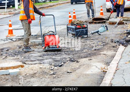 Une équipe d'entretien des routes répare les trous d'égout sur une section de la chaussée. Banque D'Images