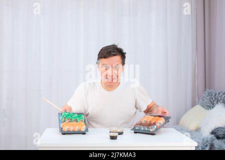 L'homme d'âge moyen caucasien propose d'essayer la nourriture asiatique de sushi dans des récipients de livraison, copyspace Banque D'Images
