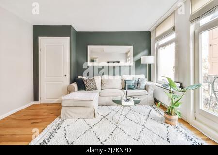 Canapé d'angle doux avec coussins dans un salon élégant avec table dans un appartement moderne lumineux décoré de plantes Banque D'Images