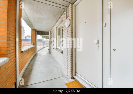 Passage étroit sur terrasse dans un bâtiment résidentiel moderne avec murs en briques et sol en béton dans la ville Banque D'Images