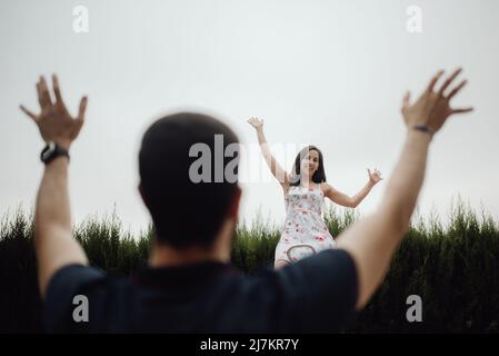 Joyeux couple décontracté en s'amusant sur le terrain de jeu serre les bras de mer dans le champ vert et en regardant l'un vers l'autre Banque D'Images