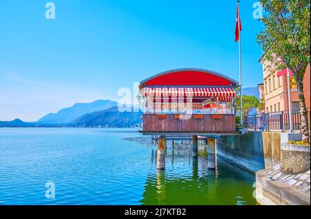 Le pittoresque lac de Lugano, entouré de montagnes et de maisons colorées de Morcote, avec une vue sur le petit pavillon de restaurant sur pilotis à l'avant Banque D'Images