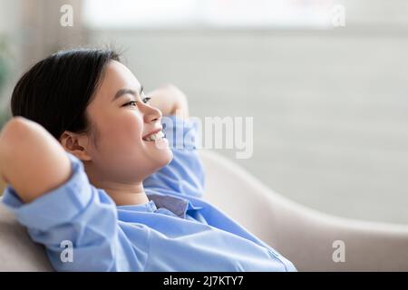 Jeune femme asiatique joyeuse appréciant le week-end à la maison Banque D'Images
