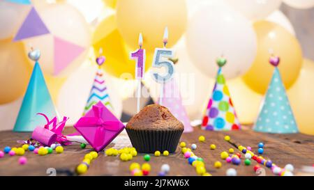 Joyeux anniversaire avec des bougies sur fond de ballons. Un muffin festif aux bougies allumées et une boîte cadeau rose pour une fille. Joyeux anniversaire fille Banque D'Images