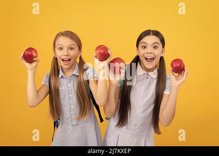 Les enfants heureux tiennent des pommes pour une collation saine de retour à l'école fond jaune, l'alimentation scolaire Banque D'Images