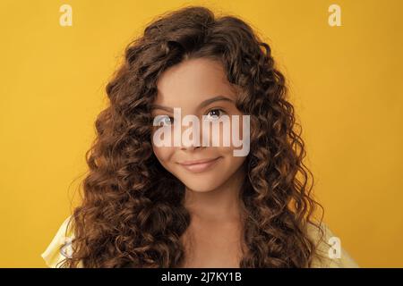 enfant souriant avec de longs cheveux bouclés et une peau parfaite, frisée Banque D'Images