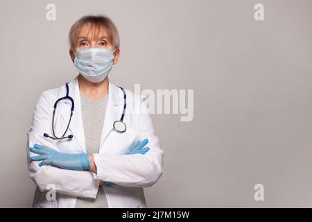 Portrait d'une femme âgée médecin portant un uniforme médical blanc debout isolé sur fond gris studio, femme mature infirmière médicale ou praticien wi Banque D'Images