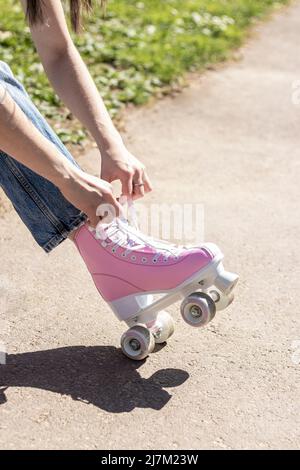 jambes d'une femme qui noue des patins à roulettes roses Banque D'Images