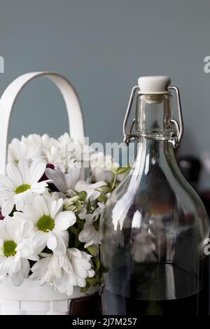 Teinture maison de cerises rouges dans une bouteille en verre sur fond gris, gros plan. Le concept des boissons alcoolisées aux baies. Banque D'Images