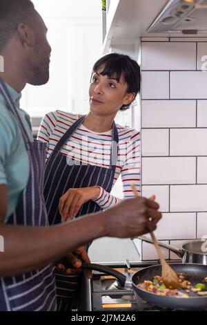 Un jeune couple multiracial cuisant des aliments ensemble à la maison Banque D'Images