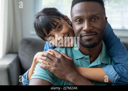 Portrait d'un jeune couple multiracial souriant qui passe du temps libre ensemble à la maison Banque D'Images