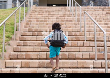 Vue arrière de l'école élémentaire afro-américaine avec marche-pied pour monter un sac à dos Banque D'Images