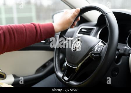 Poznan, Pologne - 20 avril 2022 Homme buvant une voiture Volkswagen. Roue en cuir et main d'homme sur elle. Banque D'Images