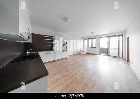 Celadna, Czechia - 05.07.2022: Chambre vide avec parquet et cuisine moderne blanche et noire. Murs et plafond blancs. Banque D'Images