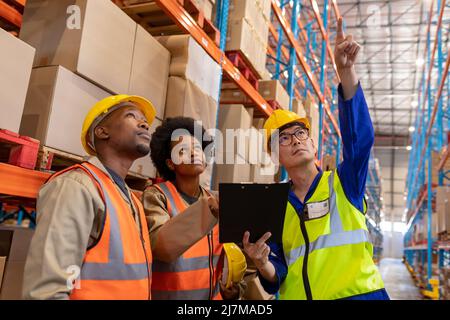 Contremaître asiatique mature pointant vers le haut et jeunes afro-américains, hommes et femmes, recherchant Banque D'Images