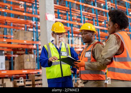 Contremaître asiatique mature expliquant au-dessus du presse-papiers à de jeunes collègues afro-américains de sexe féminin et masculin Banque D'Images