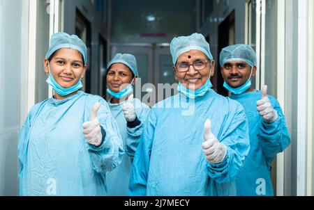 groupe souriant de chirurgiens montrant les pouces vers le haut pendant que dans le couloir de hongptal après la chirurgie - concept de traitement réussi, médecins et Banque D'Images